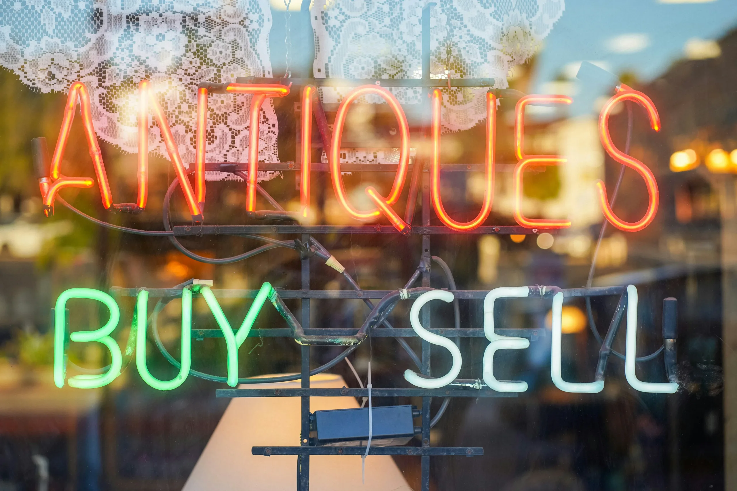 Neon sign displaying the words “antiques: buy and sell,” representing vintage and collectible items available through Messina & Park’s estate sales in NJ, NY, and CT.
